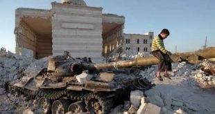 طفل يجلس على أنقاض دبابة مدمرة وسط منازل ومسجد مهدم. (الإنترنت).