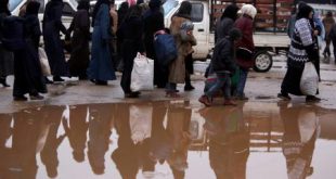 نازحون سوريون من شرق حلب يسيرون بجانب بركة مياه في منطقة تسيطر عليها الحكومة في حلب. (رويترز).