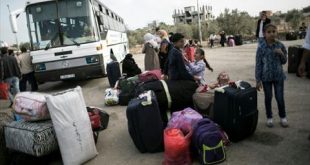 فلسطينيون ينتظرون قرب حافلة عند معبر رفح قبل عبورها إلى مصر. (فرانس برس).
