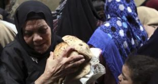 امرأة تحمل أرغفة خبز بعد شرائها من مخبز في القاهرة. رويترز.