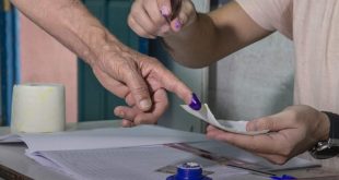 أحد أعضاء لجنة الانتخابات يقوم بمتابعة تصويت أحد المواطنين  في أحد مراكز الاقتراع خلال استفتاء على الدستور الجديد في تونس