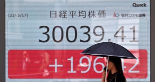 امرأة يابانية تمر أمام لوحة إلكترونية تعرض مؤشر نيكاي في أحد شوارع طوكيو، 17 مايو 2023. (أ ف ب)