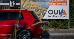 سيارة تمر من أمام لافتة انتخابية مؤيدة لمشروع قانون المناخ في لوزان، 14 يونيو 2023. (أ ف ب)