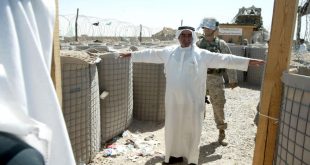 عنصر في مشاة البحرية الأمريكية يفتّش عراقيا لدى دخوله سجن أبو غريب لزيارة أحد أقربائه في مايو 2004. (أ ف ب)