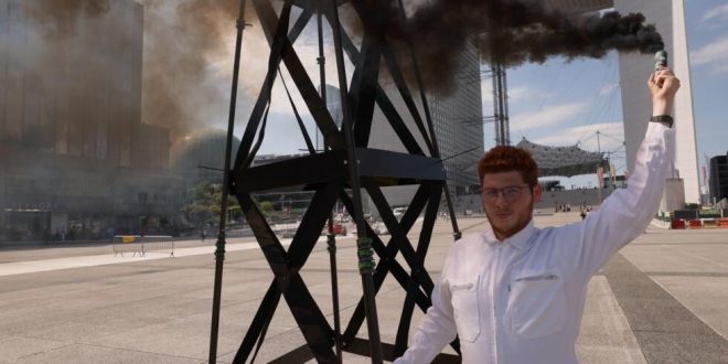 عضو في منظمة "غرينبيس" غير الحكومية يحمل شعلة دخان خلال تظاهرة ضد استغلال الوقود الأحفوري في لا ديفانس بالقرب من باريس، في 22 أغسطس 2023. (أ ف ب)